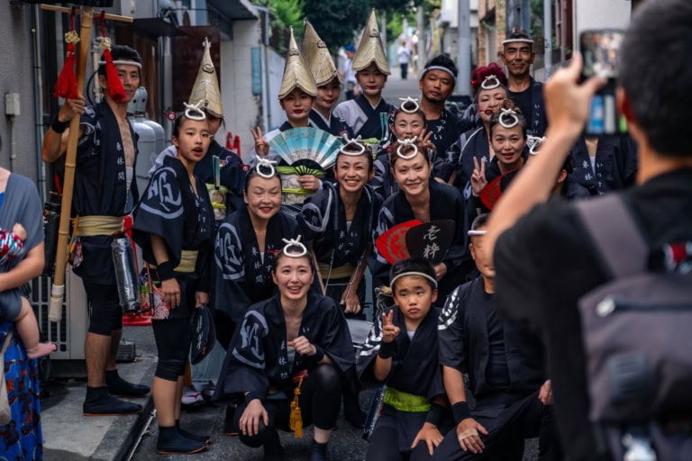 Awa Odori dancers in black happi coats and amigasa hats pose during the Shimokitazawa Awa Odori 2023.