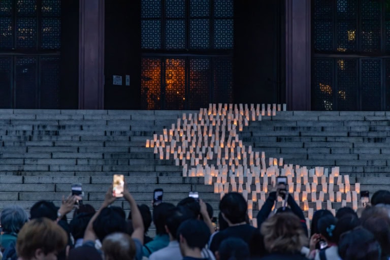 Crowds photograph a winding path of glowing lanterns on temple steps during Zojoji Tanabata at twilight.