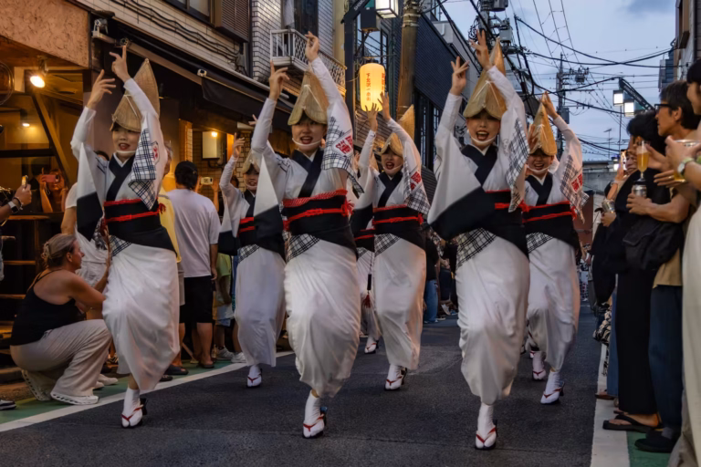 Dancers in traditional straw hats and white yukatas perform at the Shimokitazawa Awa Odori 2025 street festival.