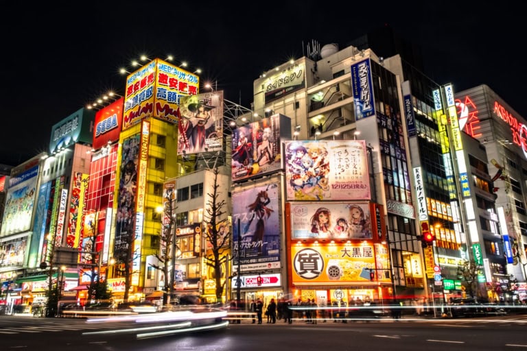 Neon signs and anime posters transform this city block into a colossal fantasy fortress of light at night.