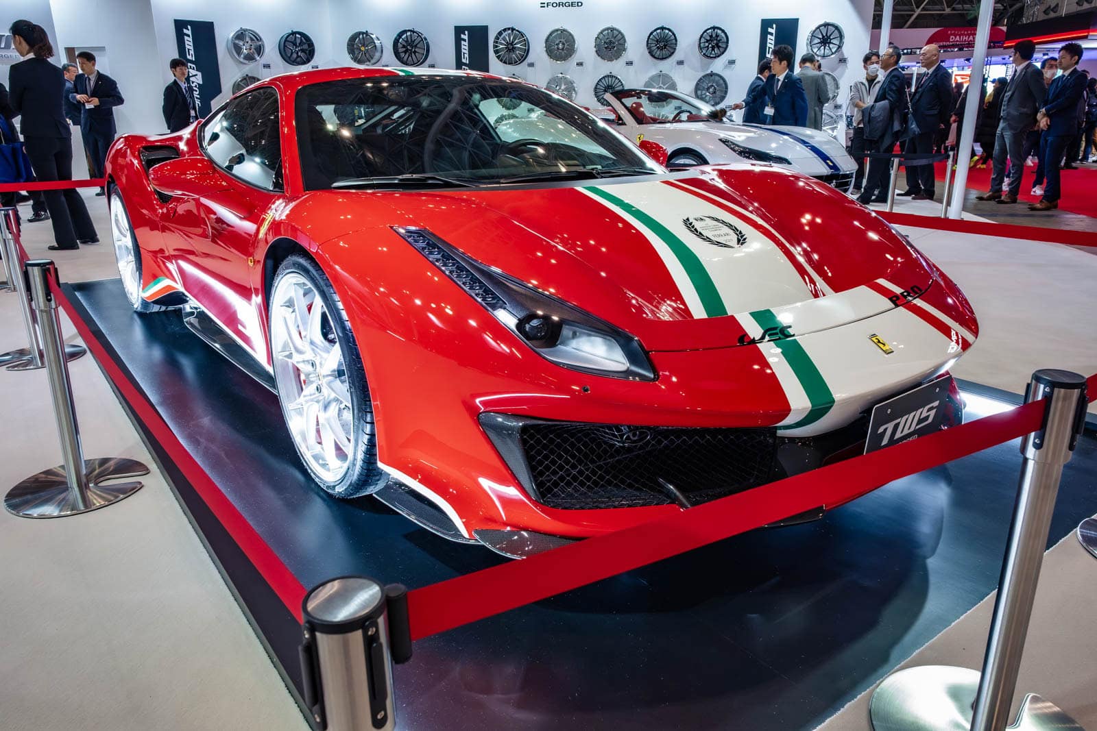 Ferrari 488 Pista at Tokyo Auto Salon 2020, shown with background wheel displays and event attendees.