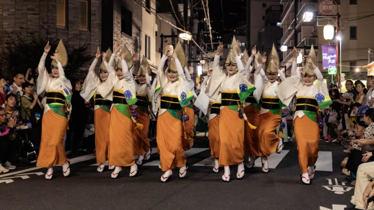Dancers in orange skirts and conical hats perform at the Hatsudai Awa Odori.