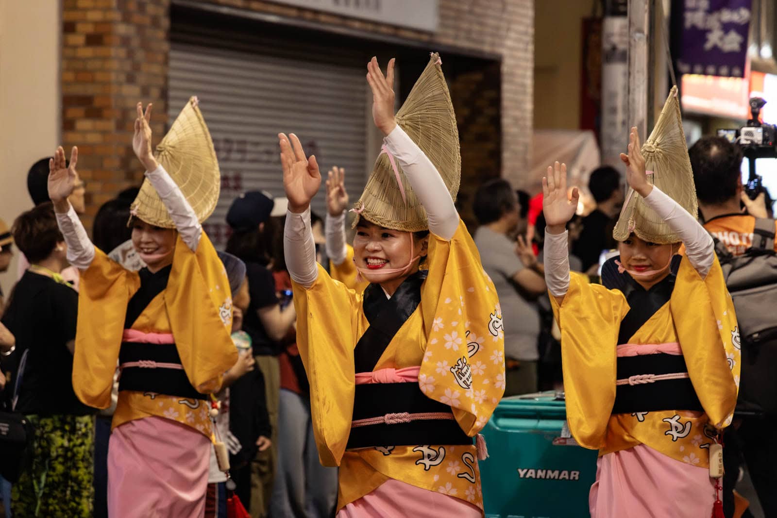 Dancers in yellow and pink kimonos with straw hats perform at the Hatsudai Awa Odori.