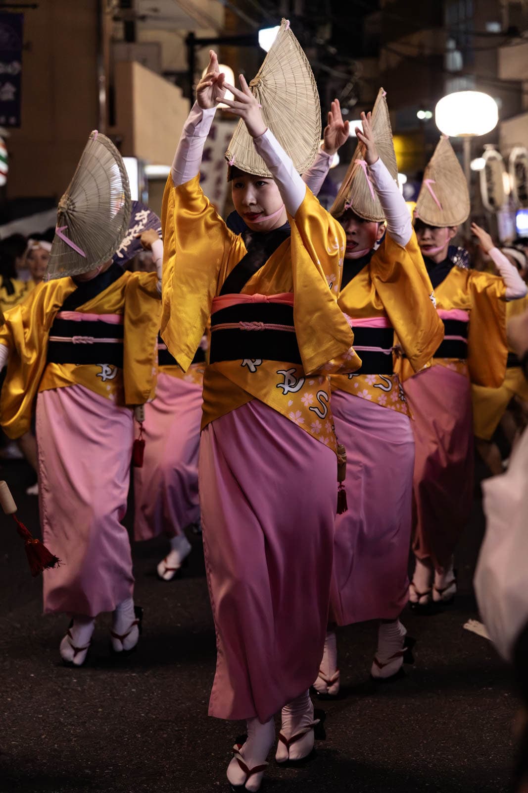 Dancers in yellow and pink kimonos with straw hats perform at the Hatsudai Awa Odori.