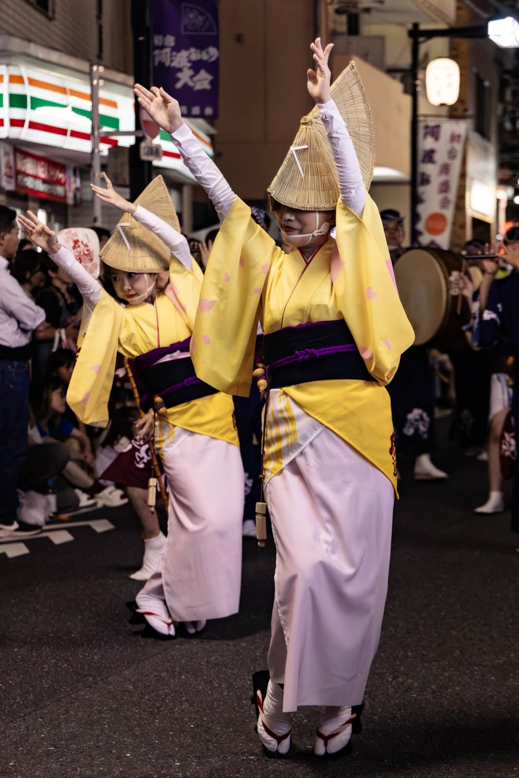 Performers in yellow and pink kimonos with straw hats dance at the Hatsudai Awa Odori.