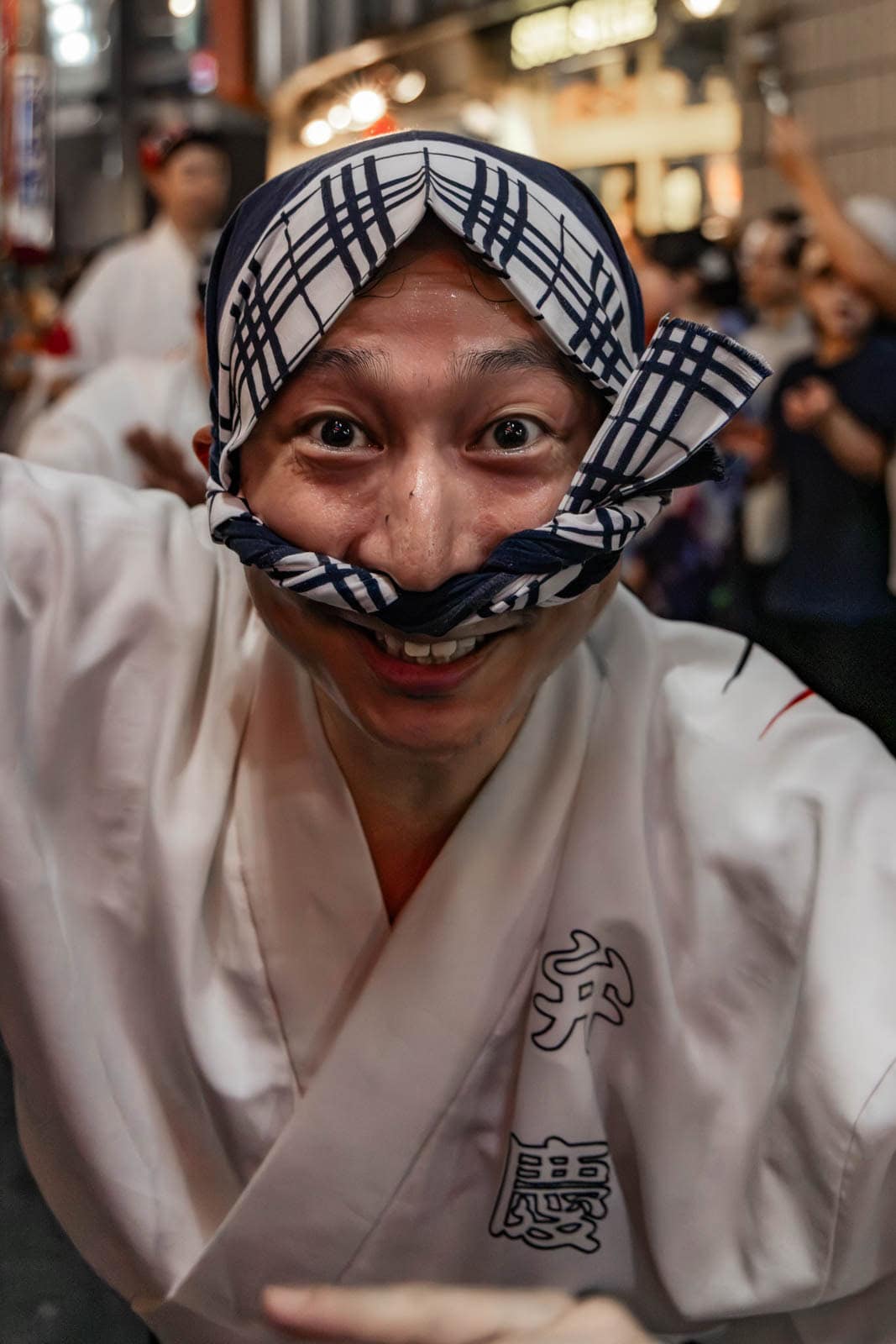 Tight cropping on a joyful Shimokitazawa Awa Odori dancer making a funny face with a headcloth mustache.