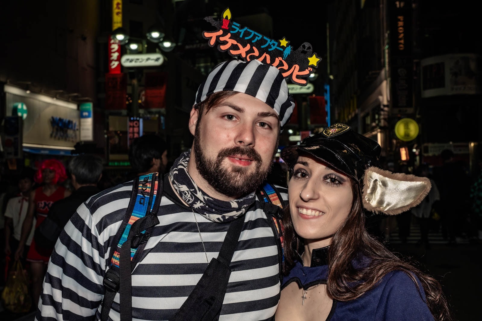 Foreign Halloween cosplayers in convict and police costumes in Shibuya at night.