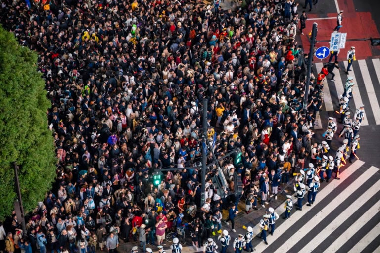 Massive Halloween crowds and police officers at Shibuya Scramble Crossing.