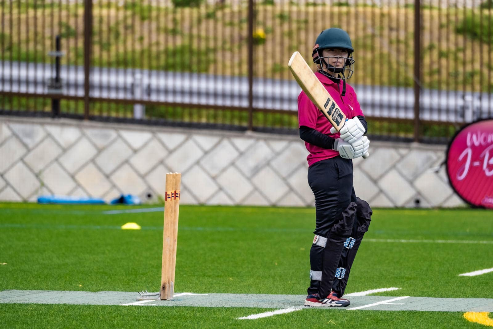 A Japanese batter standing at the crease holding a cricket bat during a match at BST Nagasawa Sports Ground in Kanagawa.