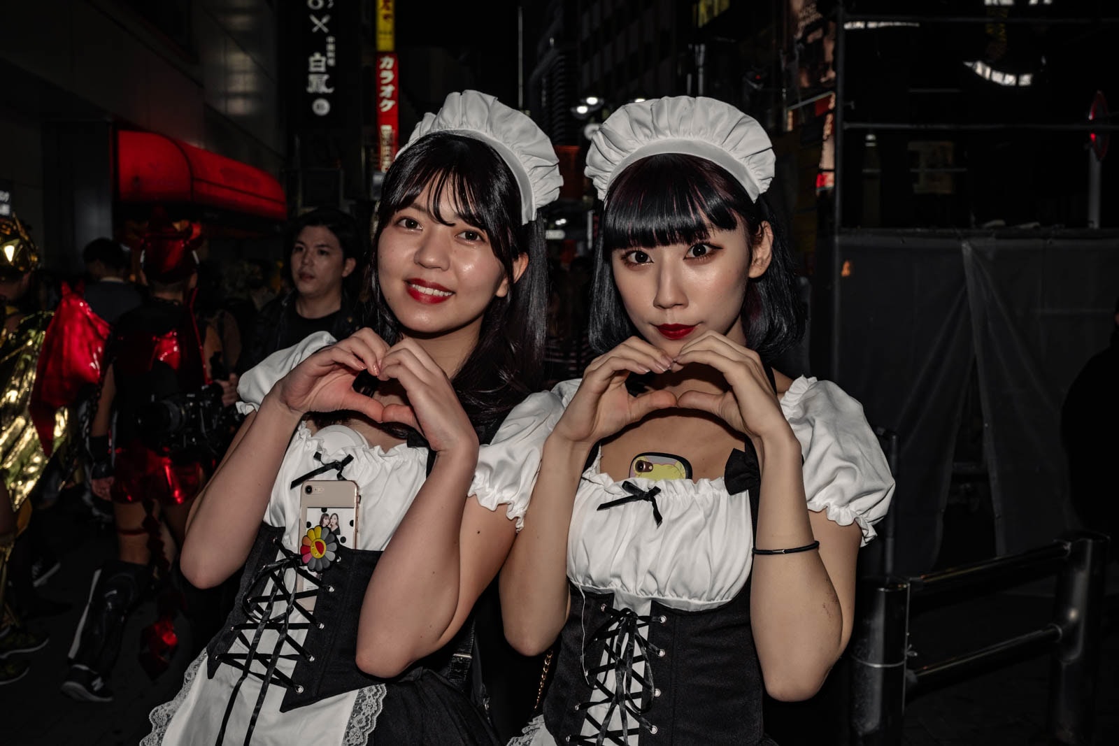 Two women in French maid costumes making heart hands during Halloween in Shibuya