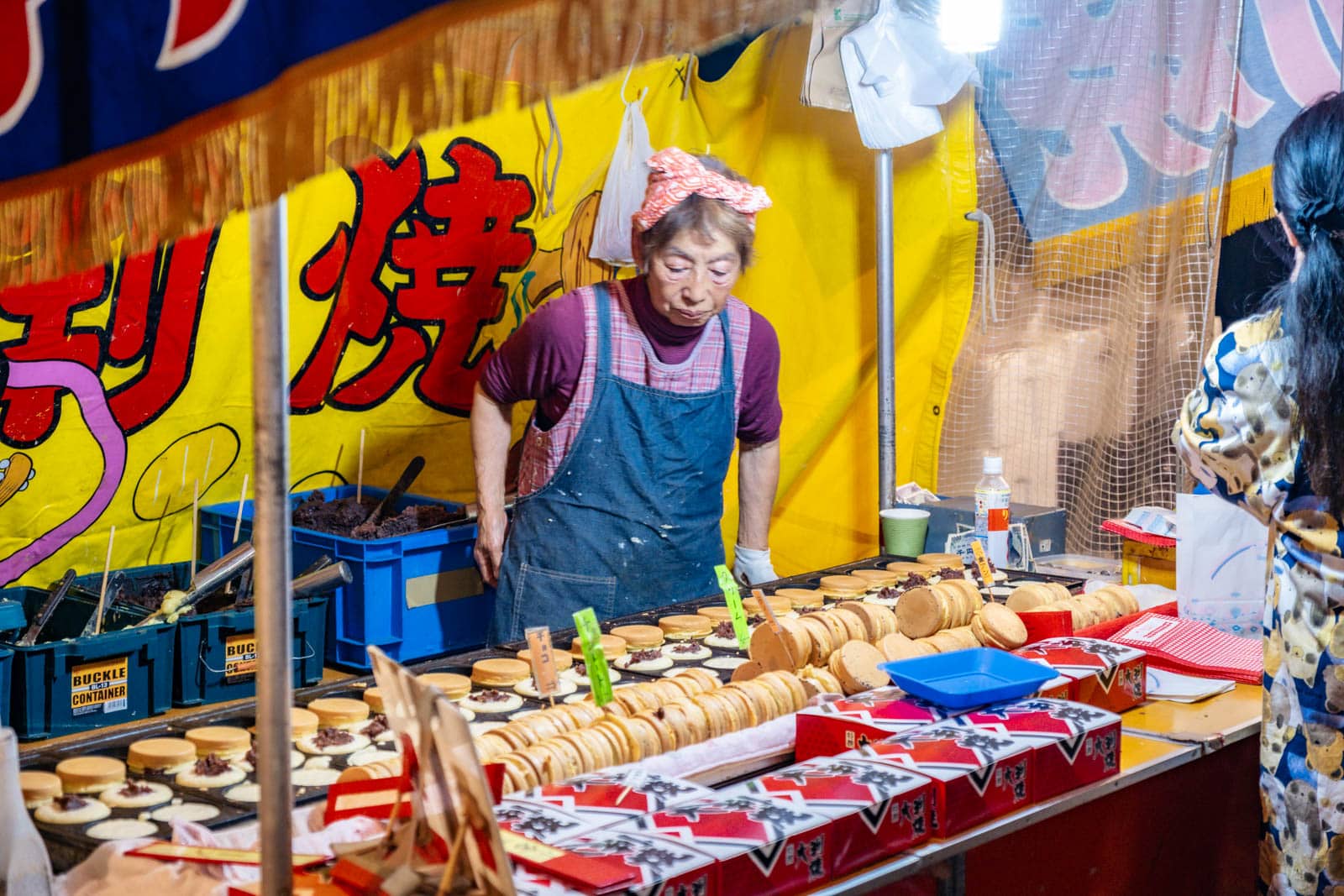 A vendor at Okunitama Shrine during the Tori-no-Ichi festival prepares sweets at a food stall.