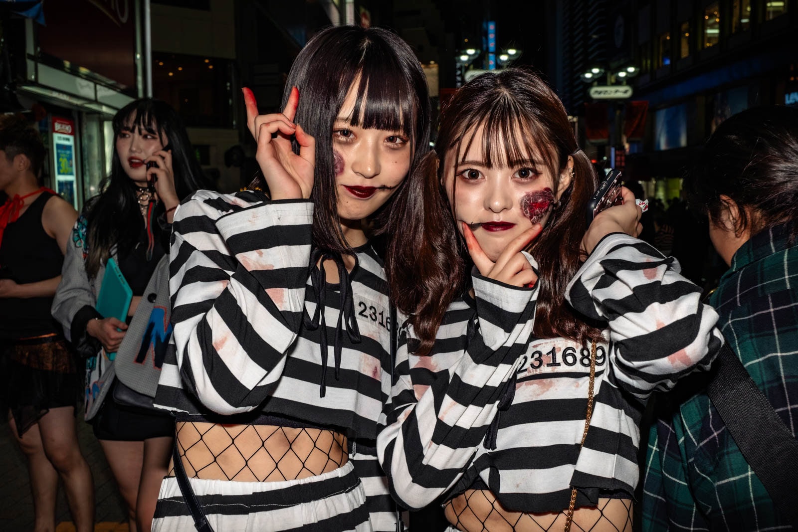 Two Japanese women in zombie convict costumes posing during Halloween in Shibuya.